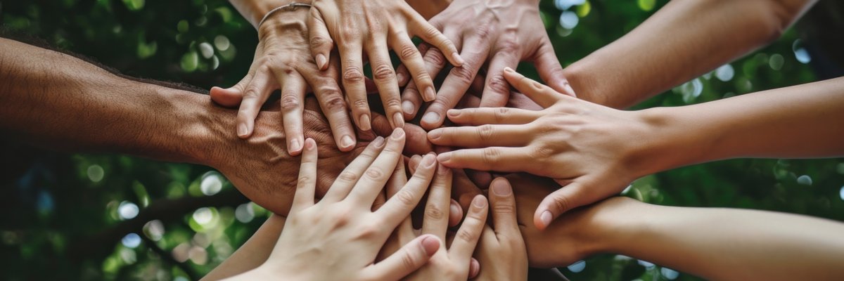 Diverse group of people standing in circle with hands together in teamwork and unity celebration concept